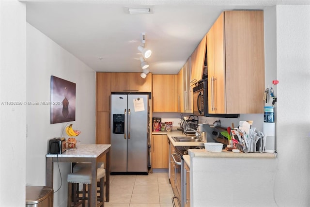 kitchen with electric range oven, stainless steel fridge, rail lighting, light tile patterned floors, and sink