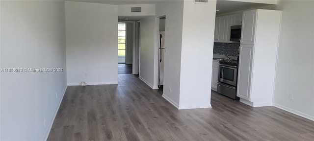 kitchen with white cabinetry, appliances with stainless steel finishes, hardwood / wood-style flooring, and tasteful backsplash