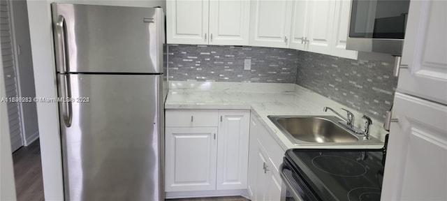 kitchen with sink, stainless steel refrigerator, white cabinetry, and tasteful backsplash