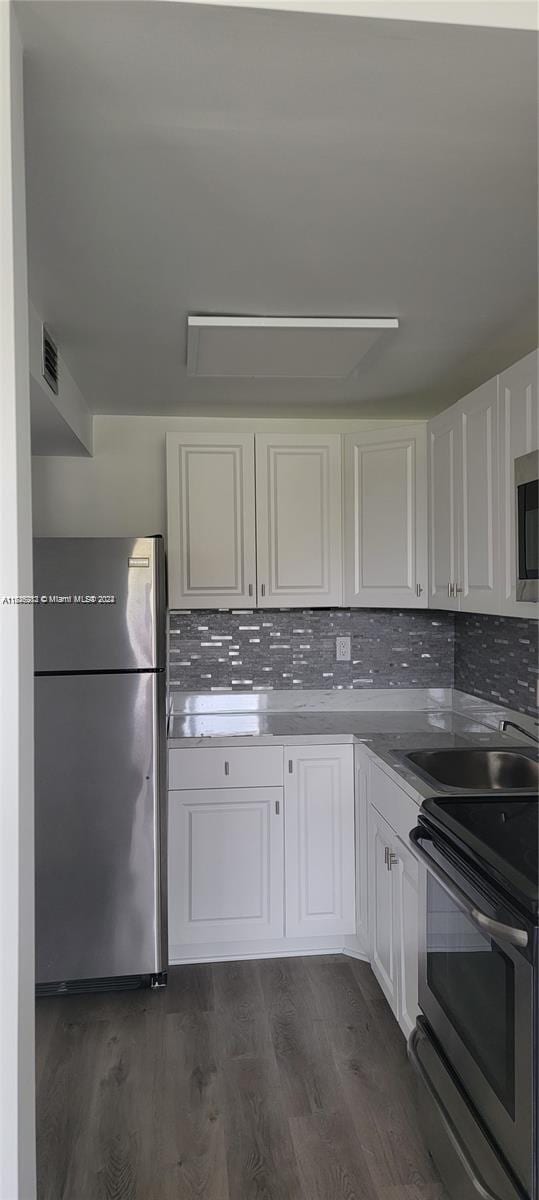 kitchen featuring appliances with stainless steel finishes, backsplash, white cabinets, and dark hardwood / wood-style floors