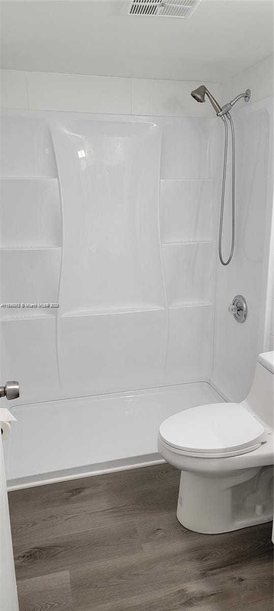 bathroom with wood-type flooring, toilet, and shower / tub combination