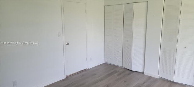 unfurnished bedroom featuring multiple closets and hardwood / wood-style floors