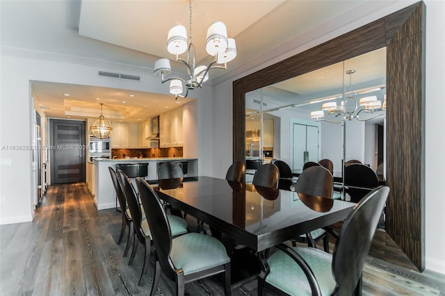 dining room with a chandelier, dark wood-type flooring, and a tray ceiling