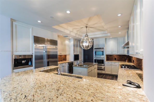 kitchen with tasteful backsplash, white cabinets, hanging light fixtures, and appliances with stainless steel finishes