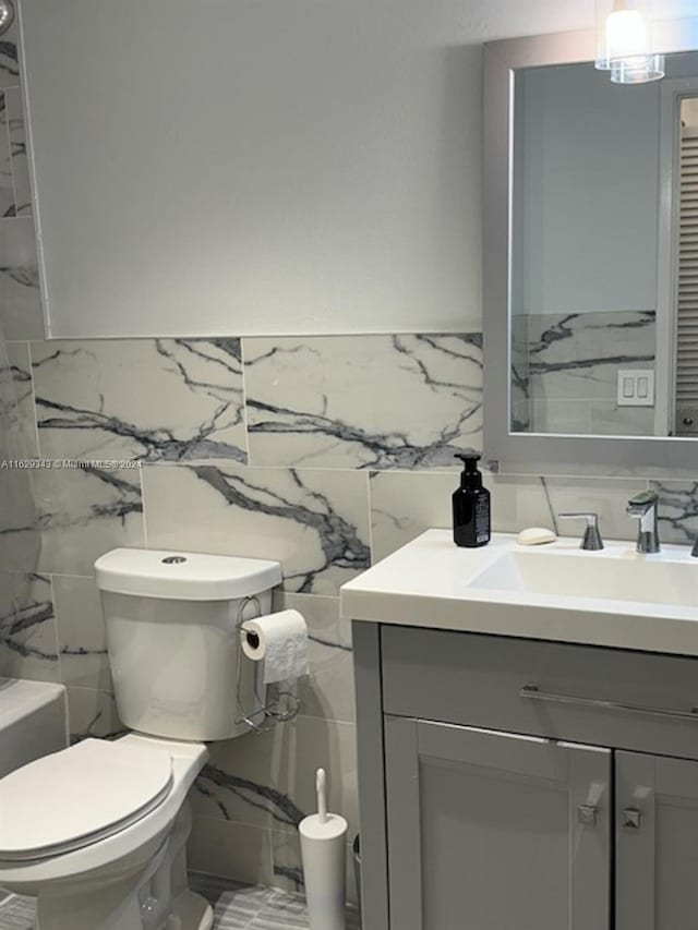 bathroom featuring tile walls, toilet, and vanity