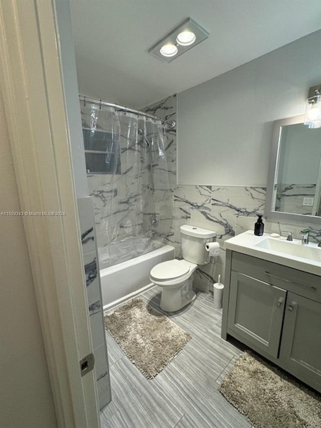 full bathroom with tiled shower / bath, toilet, vanity, tile walls, and tile patterned floors