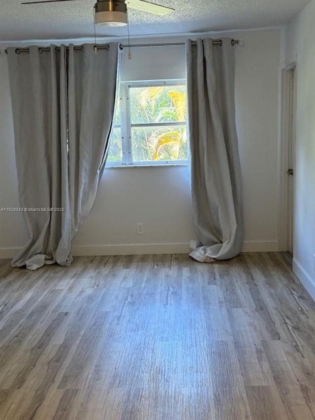 empty room featuring a textured ceiling, hardwood / wood-style flooring, and ceiling fan