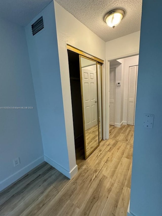 corridor with wood-type flooring and a textured ceiling