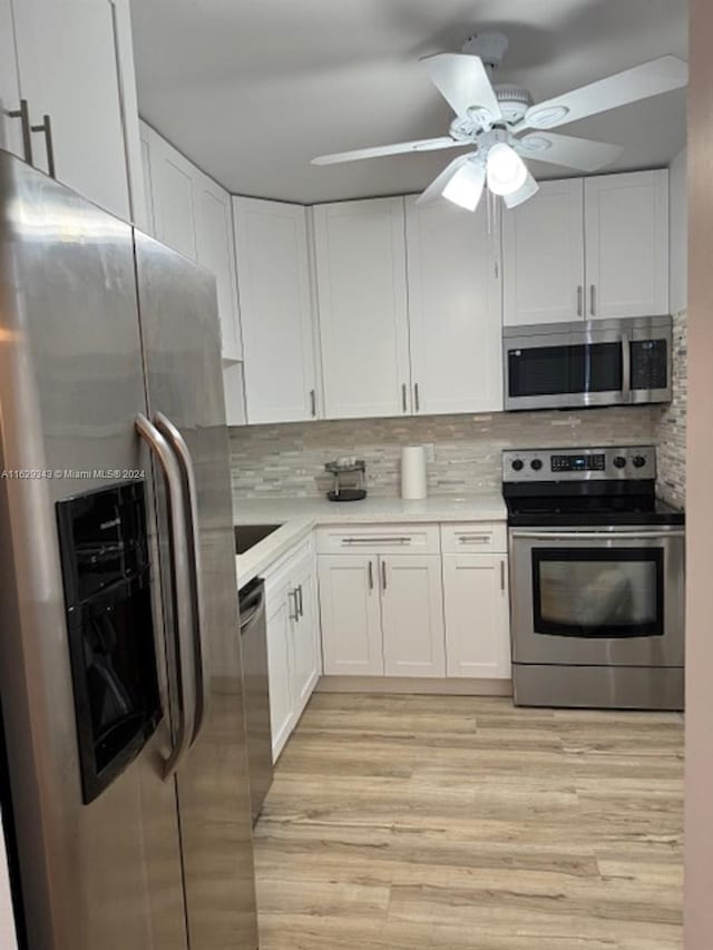 kitchen featuring decorative backsplash, appliances with stainless steel finishes, light wood-type flooring, and ceiling fan