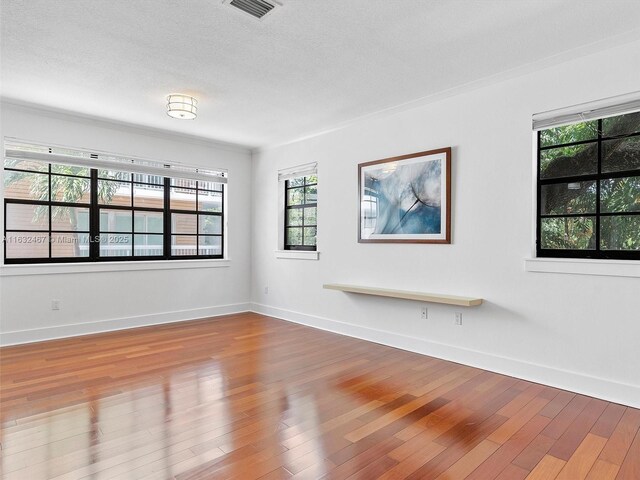 unfurnished living room featuring wood-type flooring, ornamental molding, and a textured ceiling