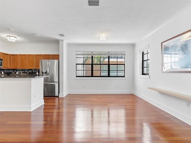 kitchen featuring wood-type flooring, appliances with stainless steel finishes, a textured ceiling, and decorative backsplash