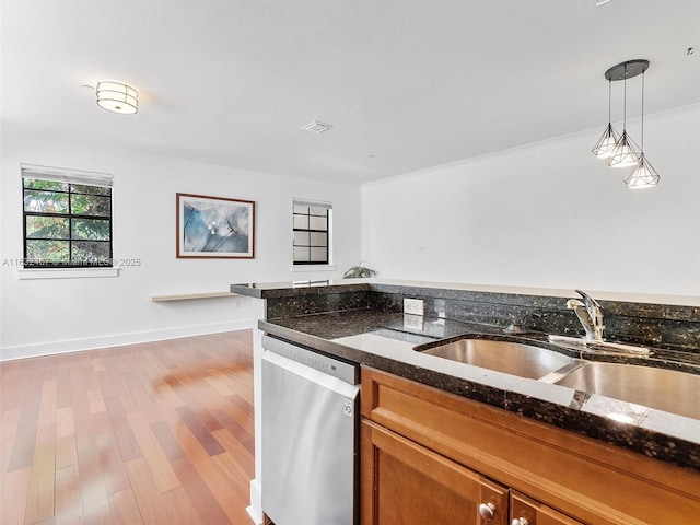 kitchen featuring sink, hanging light fixtures, hardwood / wood-style floors, stainless steel dishwasher, and dark stone counters