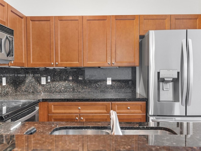 kitchen with dark stone countertops, sink, backsplash, and appliances with stainless steel finishes