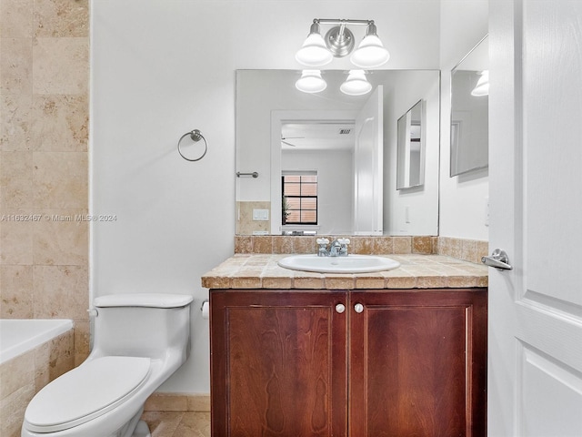 bathroom featuring vanity, a tub to relax in, and toilet