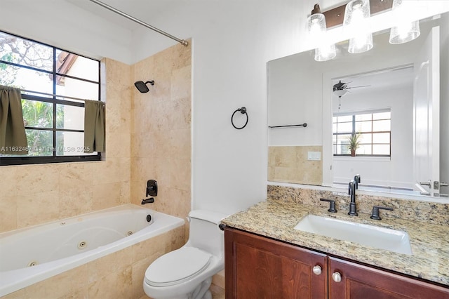 full bathroom with vanity, tiled shower / bath, toilet, and ceiling fan