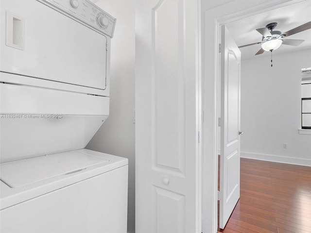 clothes washing area with dark wood-type flooring, ceiling fan, and stacked washing maching and dryer