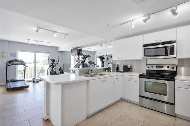 kitchen with sink, track lighting, kitchen peninsula, stainless steel appliances, and white cabinets