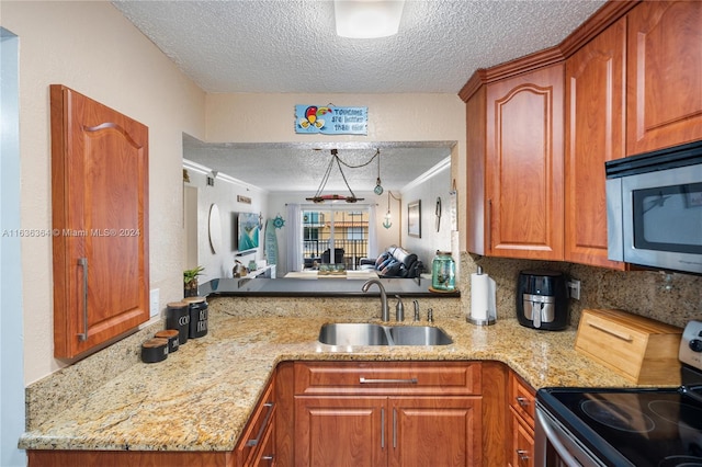 kitchen with sink, stainless steel appliances, light stone counters, a textured ceiling, and decorative backsplash