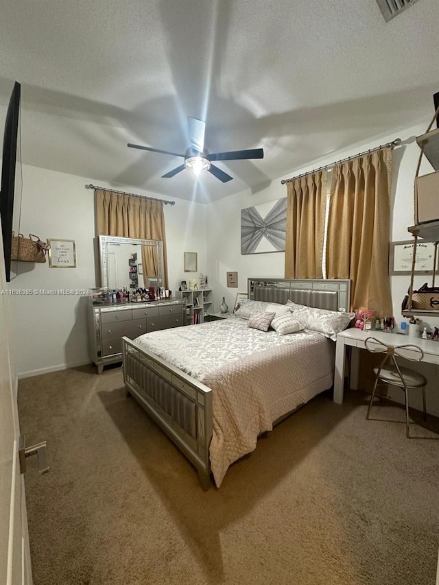 carpeted bedroom featuring ceiling fan and a textured ceiling