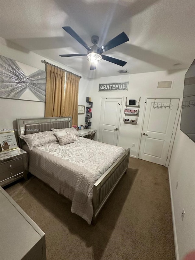 bedroom with ceiling fan, a textured ceiling, and dark colored carpet