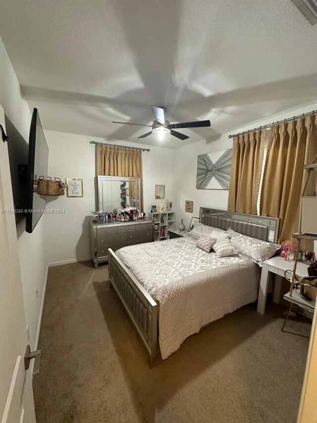 carpeted bedroom with ceiling fan and a textured ceiling