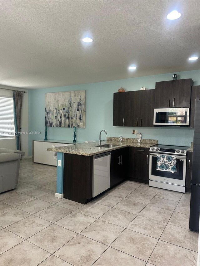 kitchen with kitchen peninsula, a textured ceiling, stainless steel appliances, and sink