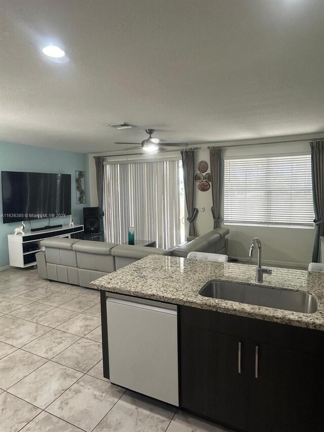 kitchen with ceiling fan, sink, light stone counters, and light tile patterned floors