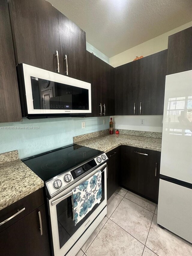 kitchen featuring dark brown cabinets, electric range, and white fridge