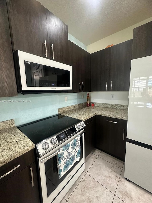 kitchen with white refrigerator, stainless steel electric stove, dark brown cabinets, and a textured ceiling