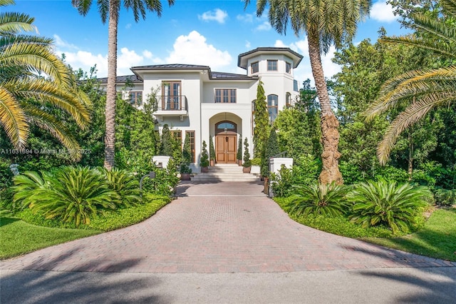 mediterranean / spanish-style home featuring a standing seam roof, metal roof, a balcony, and stucco siding