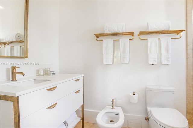 bathroom featuring toilet, a bidet, and vanity