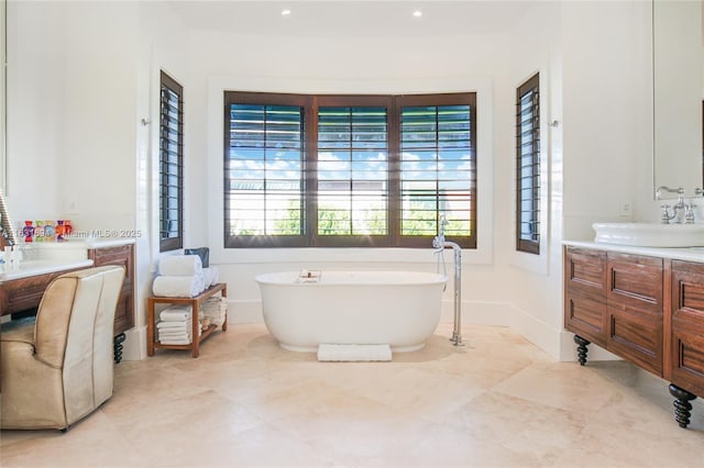 full bathroom featuring recessed lighting, a soaking tub, vanity, and baseboards