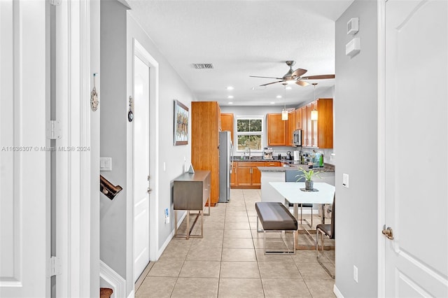 kitchen featuring a textured ceiling, light tile patterned flooring, stainless steel appliances, and ceiling fan