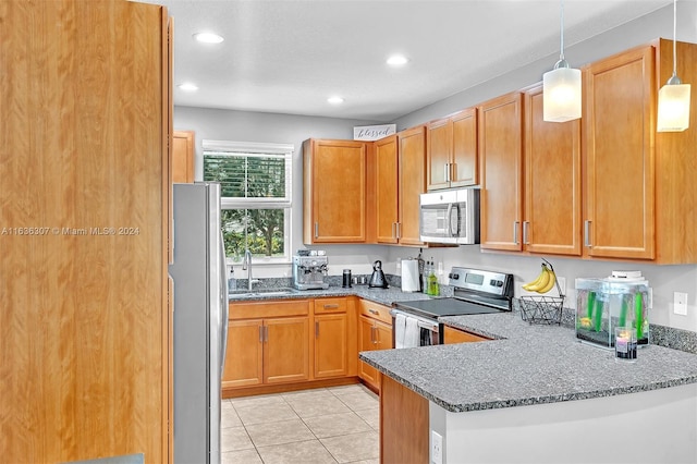 kitchen with sink, kitchen peninsula, stainless steel appliances, pendant lighting, and dark stone countertops