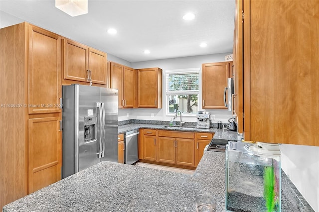 kitchen featuring sink, appliances with stainless steel finishes, and dark stone countertops