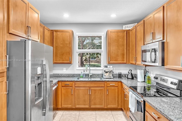 kitchen with light stone countertops, stainless steel appliances, sink, and light tile patterned floors