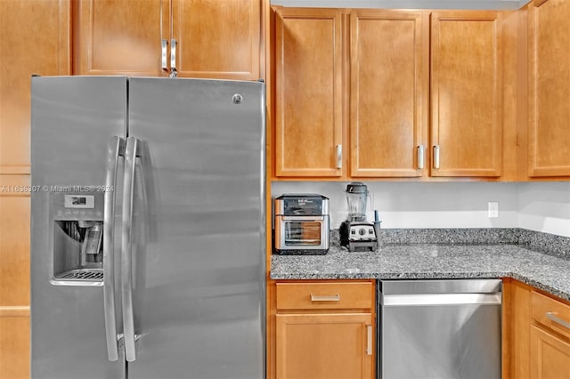 kitchen with stainless steel appliances and dark stone counters