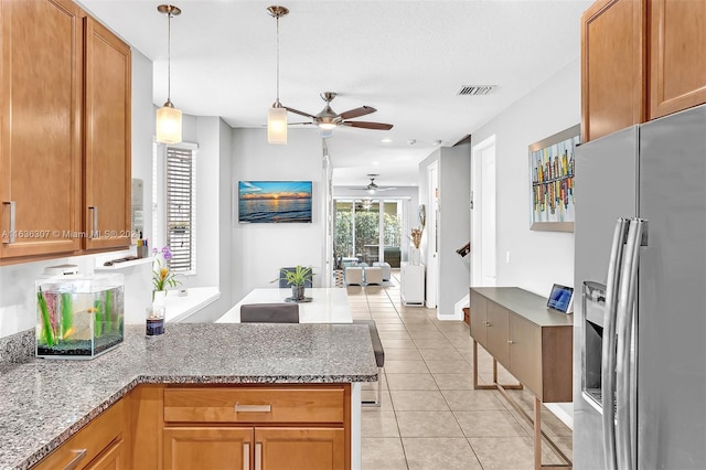 kitchen featuring ceiling fan, decorative light fixtures, light stone counters, light tile patterned floors, and stainless steel refrigerator with ice dispenser