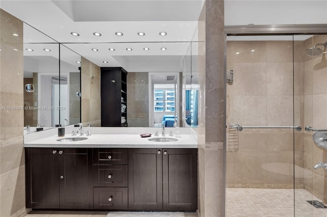 bathroom featuring tile patterned floors, a shower with door, and dual bowl vanity