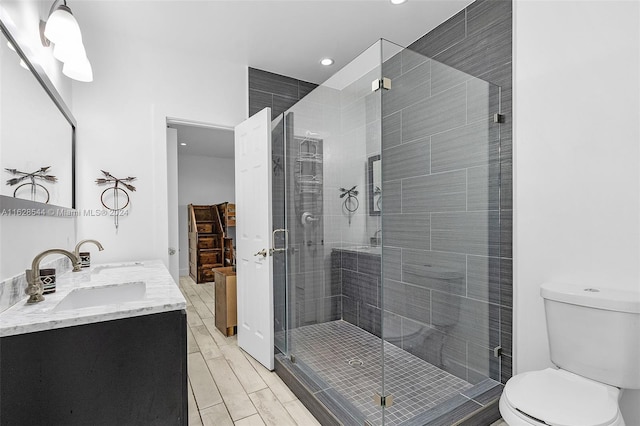 bathroom with hardwood / wood-style floors, double sink vanity, toilet, and an enclosed shower