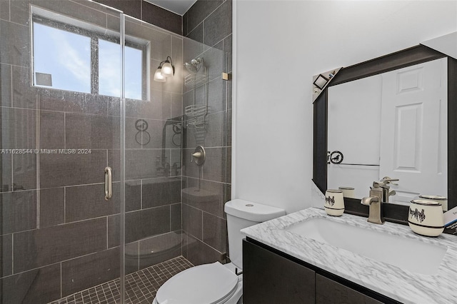 bathroom featuring a shower with door, toilet, and vanity