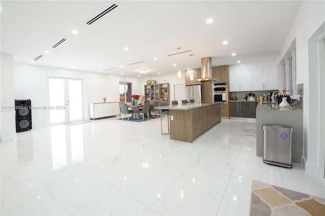 kitchen with white cabinetry, pendant lighting, a spacious island, extractor fan, and decorative backsplash