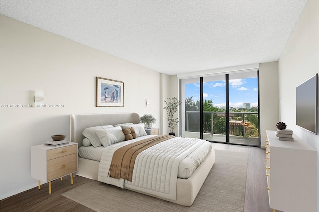 bedroom featuring access to exterior, a textured ceiling, hardwood / wood-style flooring, and a wall of windows