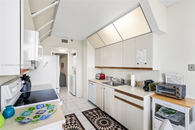 kitchen with white range oven, sink, light tile patterned floors, white cabinets, and washer / dryer