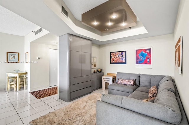 living room with light tile patterned floors and a tray ceiling