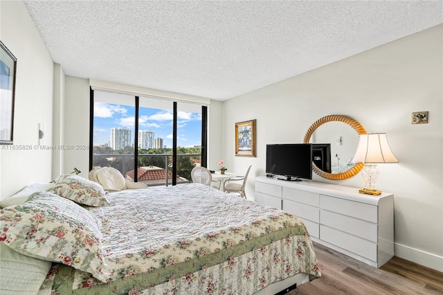 bedroom with access to outside, a textured ceiling, light hardwood / wood-style floors, and floor to ceiling windows