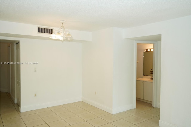 unfurnished room featuring light tile patterned flooring, an inviting chandelier, and a textured ceiling