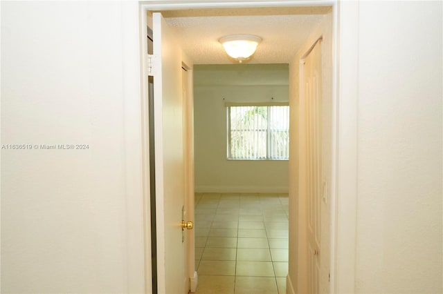 hallway featuring light tile patterned floors and a textured ceiling