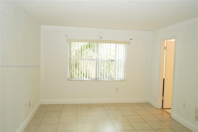 spare room featuring a textured ceiling and light tile patterned floors