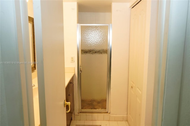 bathroom featuring a shower with shower door, vanity, and tile patterned floors